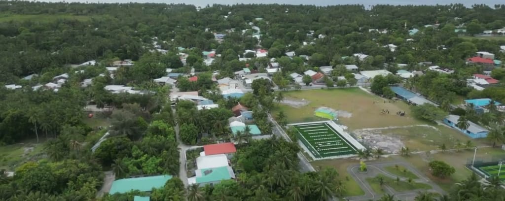 Aerial view over Fuvahmulah’s rooftops, palm canopy and the open ocean
